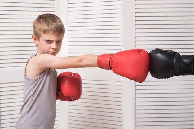 Boy in boxing gloves fights with a man's hand in a glove.