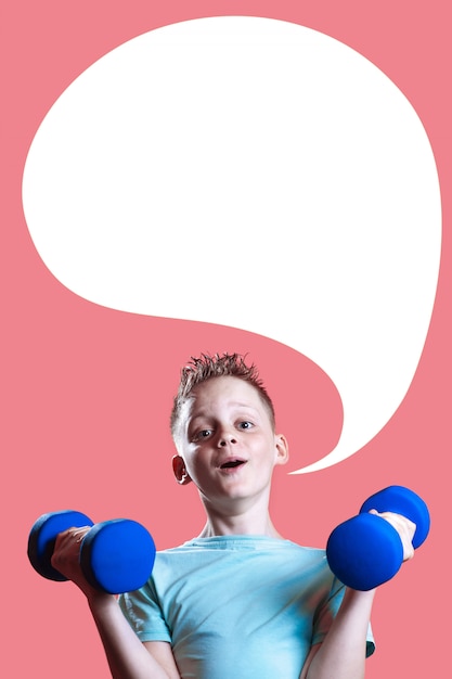 A boy in a bright t-shirt with dumbbells on a pink background