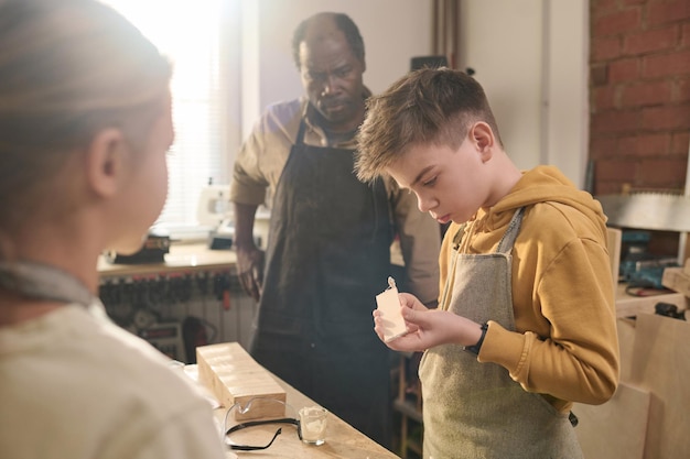 Photo boy building wooden model in carpenting workshop for children