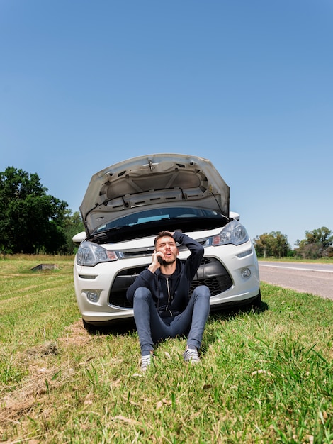 Boy calling next to broken down car