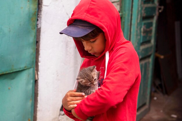 The boy carefully and lovingly holds a stray kitten on the street.