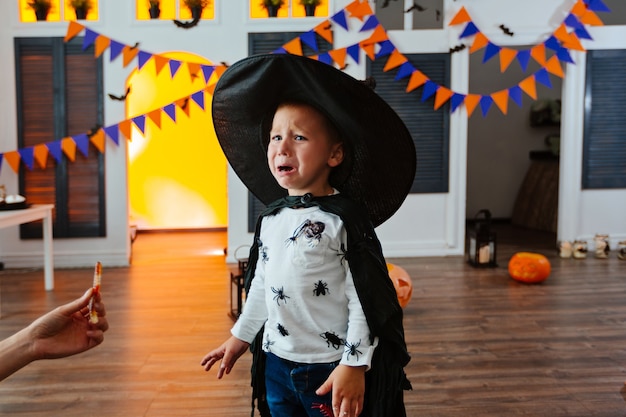 Un ragazzo con un costume di carnevale e un cappello nero va alla festa di halloween