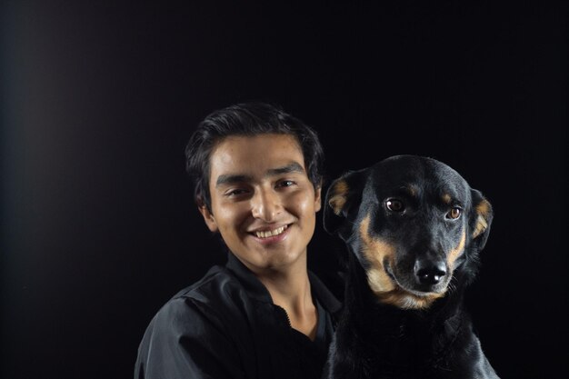 Boy carrying his dog, both posing for the picture, the dog has a tender and happy face, he feels the love of his human and has a good time.