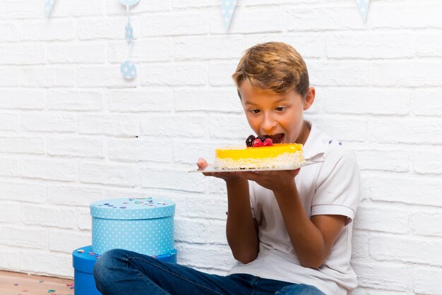 ケーキを食べて彼の誕生日を祝っている少年