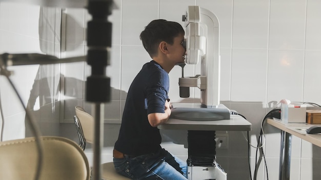 Boy checks eye vision in ophthalmology clinic, close up