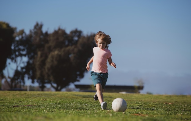 サッカーの試合中にスポーツフィールドでサッカーを蹴る男の子の子供