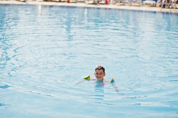 Boy in child oversleeves bathes in the pool.