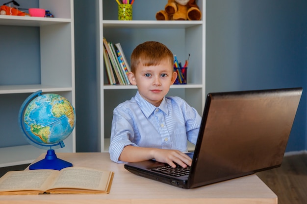 Boy child playing laptop at home.