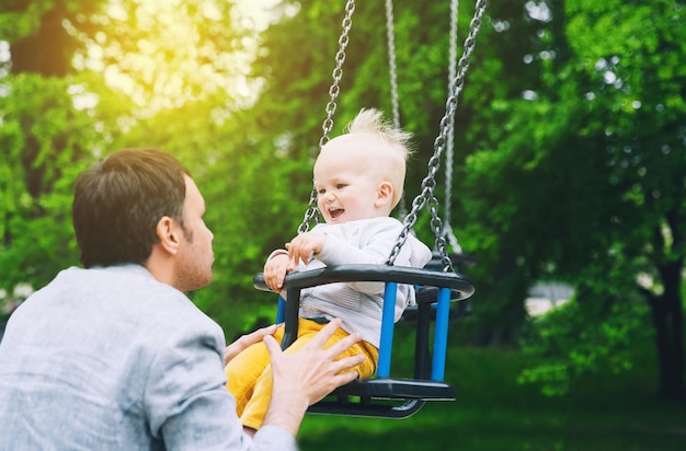 Ragazzo bambino che gioca in un parco giochi famiglia felice nel parco giochi in estate o in primavera in un parco