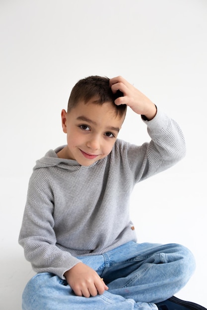 Bambino in età prescolare del bambino sorridente e in posa su sfondo grigio in studio fotografico