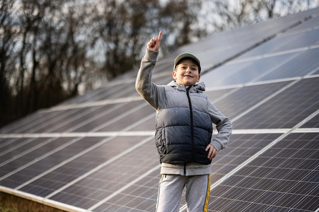 Boy child show finger up on the background of solar panels Eco energy