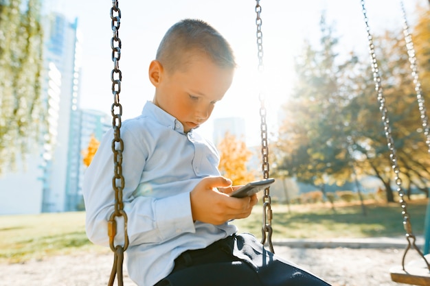 Boy child on a swing in the autumn park