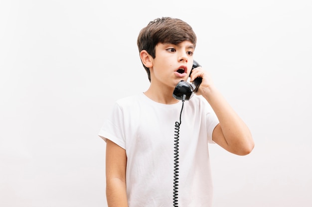 Boy child talking on vintage phone surprised