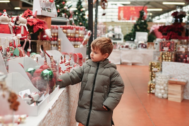 Foto un ragazzo sceglie le palle per l'albero di natale