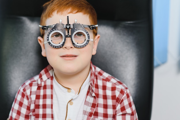 Boy choosing glasses at optics store.