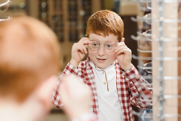 Boy choosing glasses at optics store.