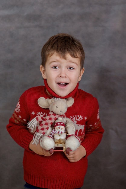 Boy in Christmas sweater with Christmas deer toy.