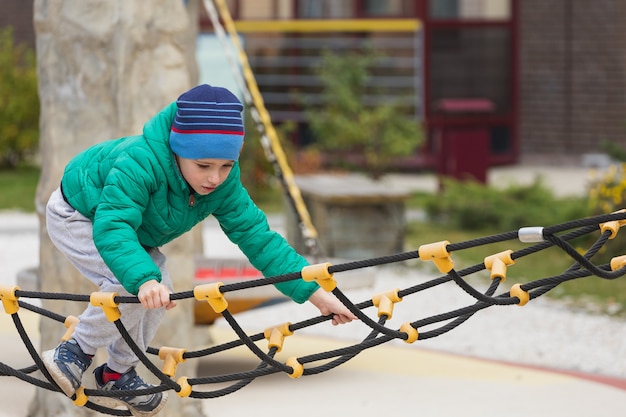 A boy climbs a rope ladder at the playground