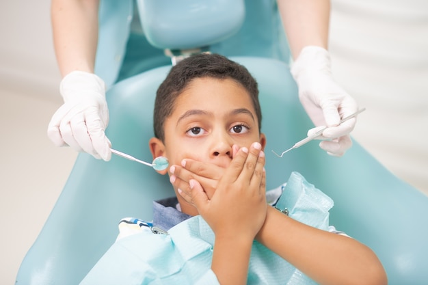 Boy closing mouth. Dark-eyed handsome boy closing his mouth while feeling scared of dentist