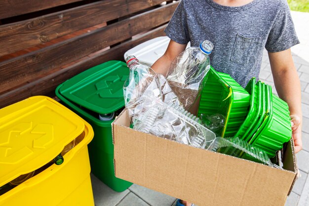 The boy collect the plastic trash into the paper box for recycling