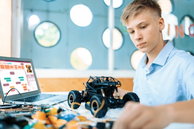 Photo boy consider parts of robotics car while learning in stem class edification