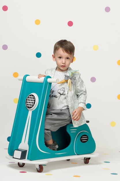 Boy in costume designer on a toy motorcycle on a white background