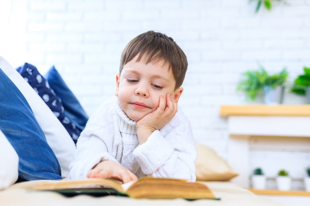 The boy on the couch is reading a book