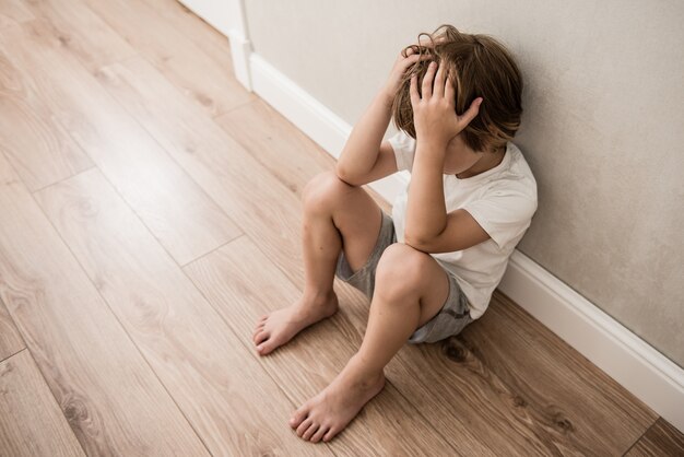 Boy crying covered his face with his hands