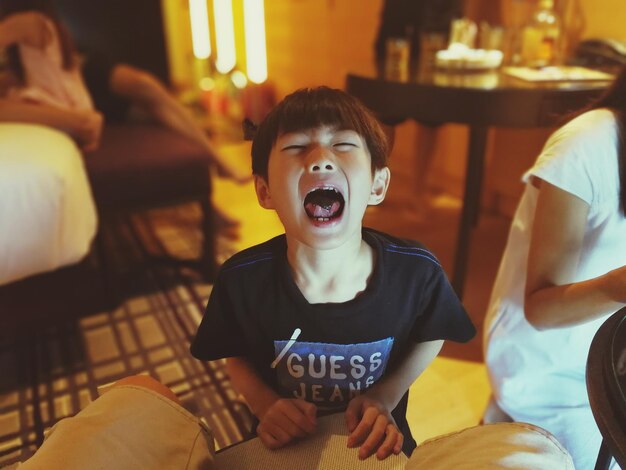 Photo boy crying while standing by chair at home