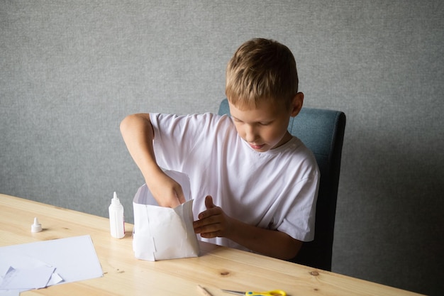 The boy cuts out details from paper Glue the parts together with glue