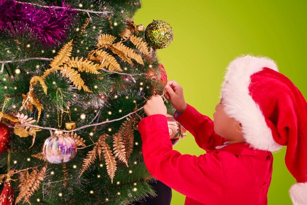 Фото Мальчик украшает рождественскую елку дома