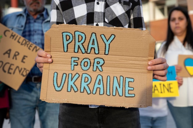 A boy demonstrator shows a cardboard sign in support of the\
ukrainian people during an antiwar street protest