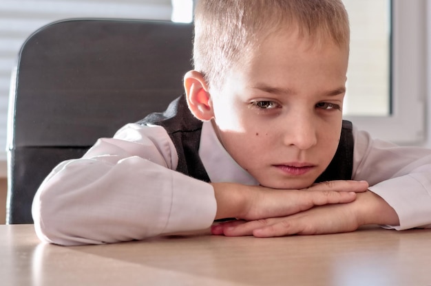 Boy at the desk put his head on his hands