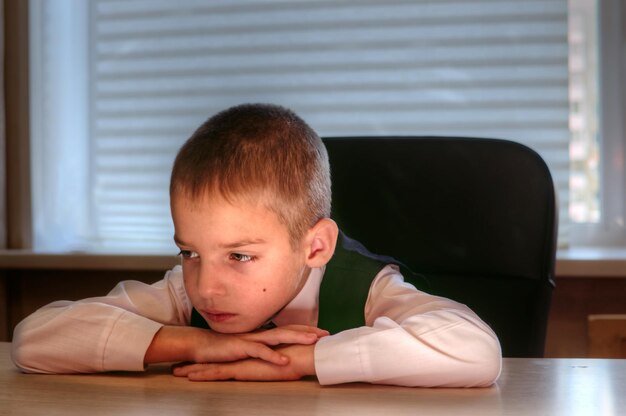 Boy at the desk put his head on his hands