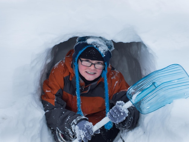 Photo boy digging a snow cave at the great teton national park.