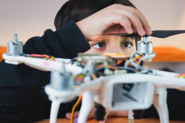 The boy diligently puts the propeller on the drone. Extracurricular physics work in the home lab. Innovative education