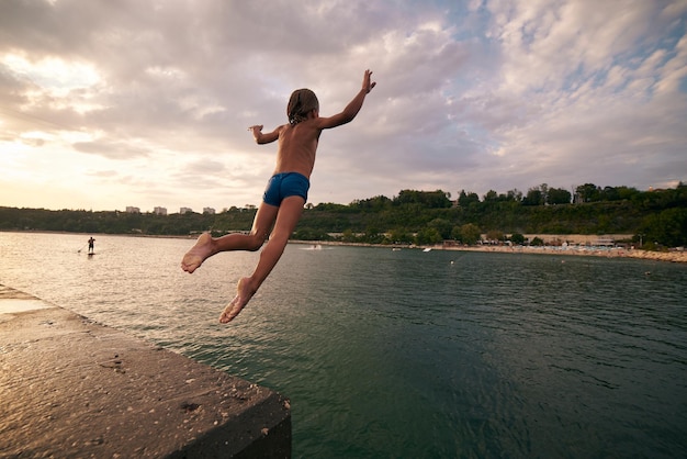 Boy dives into the sea from a pier Hot summer day