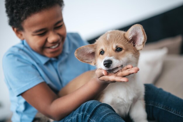 A boy and a dog. a dark-skinned boy holding a cute puppy and\
smiling