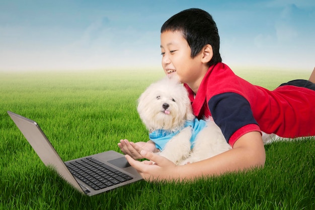 Boy and dog using laptop at field