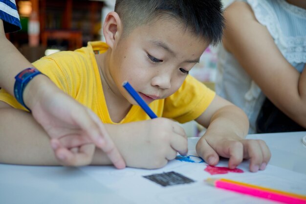 宿題をしている男の子が学校に戻って紙の教育の概念を書いている