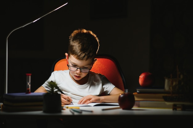 Photo boy doing homework at home in evening