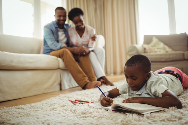 Photo boy doing homework while lying on a rug