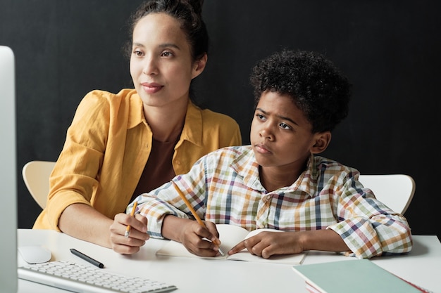 Photo boy doing homework with his mom