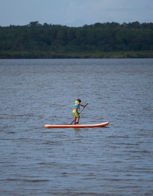 写真 湖でソロパドルサーフィンをしている少年