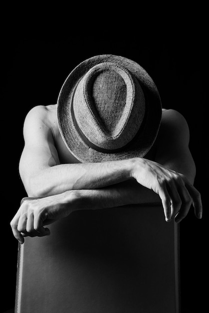 Photo boy in dramatic light with face covered by a hat