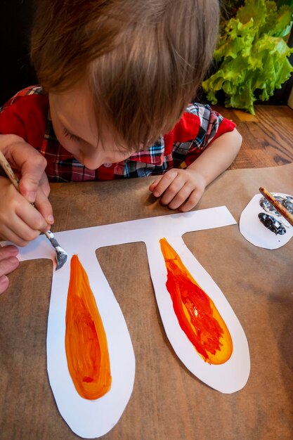 Boy drawing the ears of a handmade Easter bunny made of cardboard Preparation for the celebration of the Easter holiday