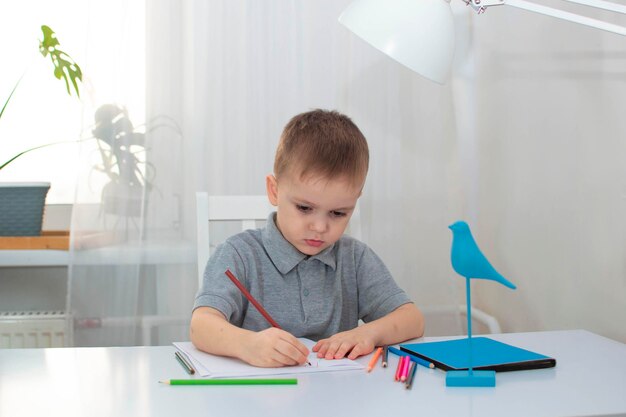 The boy draws in his room at his desk The child is engaged in creativity at home The concept of childrens creativity Selective focus