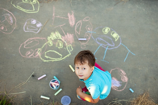 Boy draws with chalk on the pavement