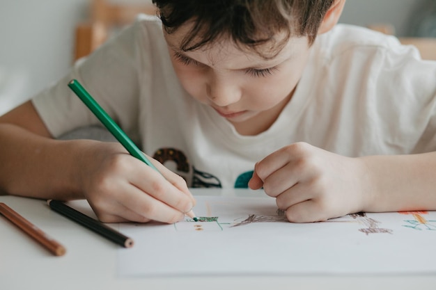 The boy draws with pencils at the kitchen closeup high quality photo