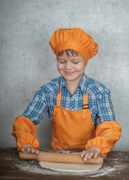 boy dressed as a cook is engaged in cooking homemade pizza